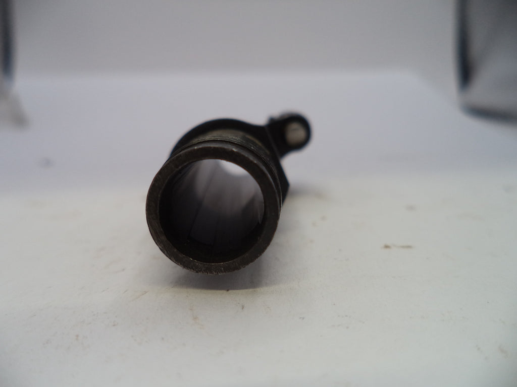 A close-up of a dark metal cylindrical component with a circular opening and a small protruding tab, resting on a white surface.
