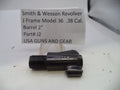 A black metal Smith & Wesson revolver barrel adapter part, model J2, shown on a white surface with a handwritten label card in the background.