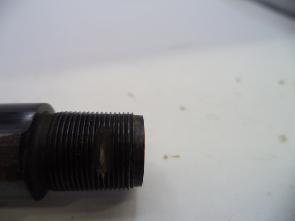 A close-up of a dark metal threaded pipe fitting or valve component on a white surface.