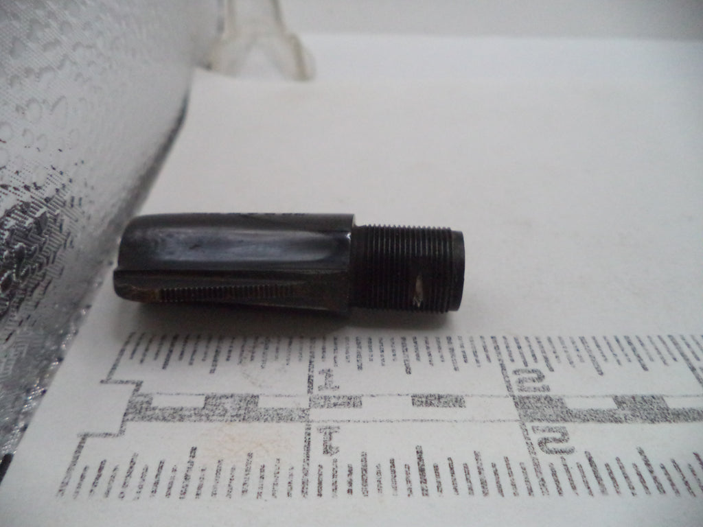 A small dark metal threaded component, possibly a mechanical fitting or valve part, resting on a printed ruler against a white background.