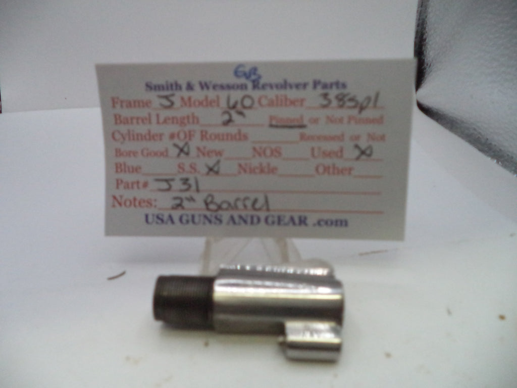 A used metal revolver part, likely a cylinder or frame component, displayed in front of a handwritten paper label card for Smith & Wesson revolver parts.