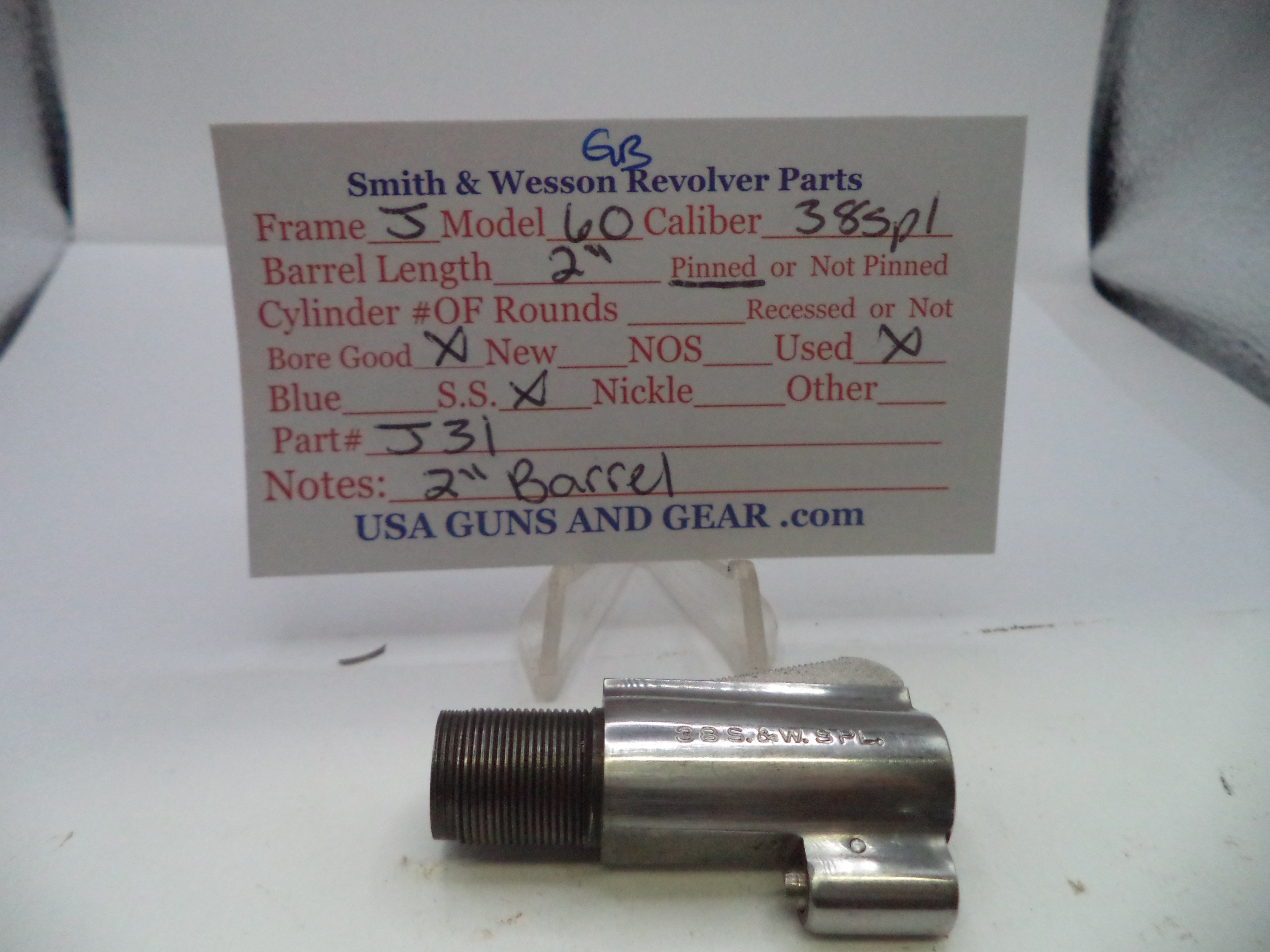 A metal Smith & Wesson revolver part displayed on a clear stand in front of a handwritten parts card for a 40 caliber revolver.
