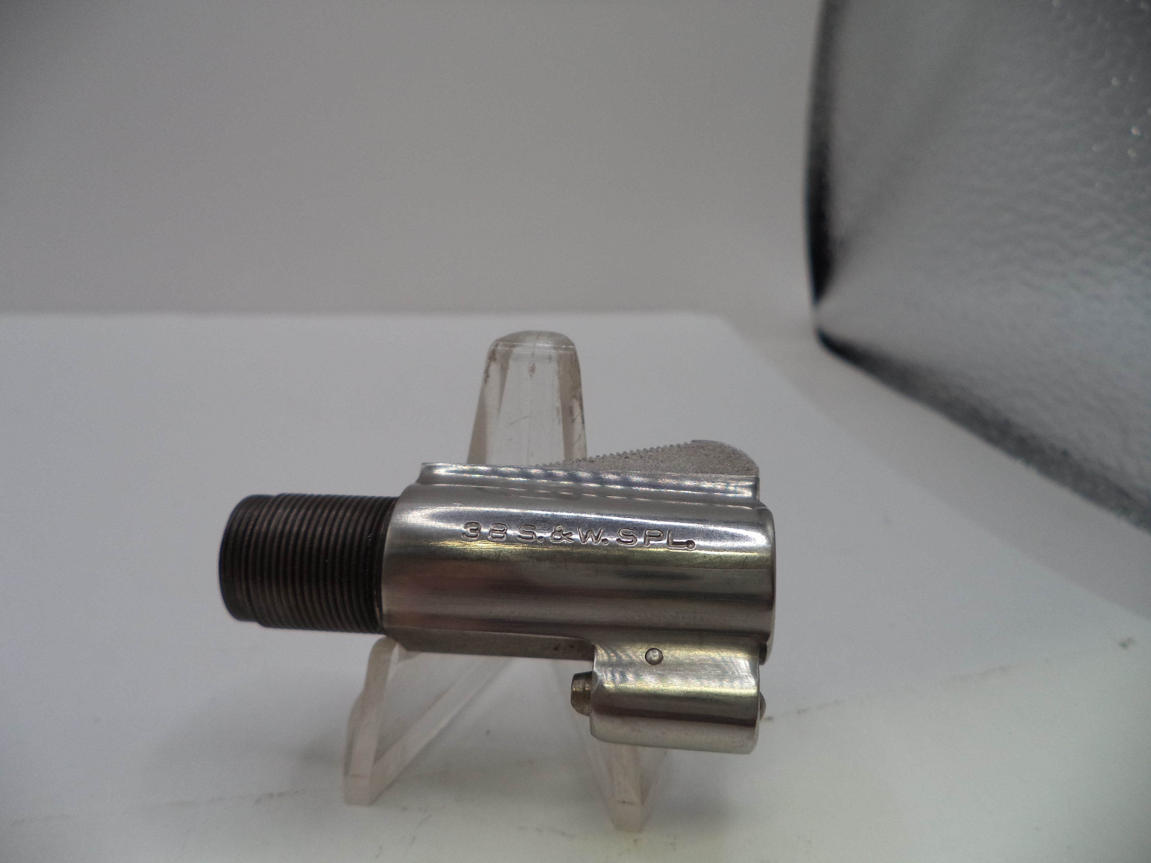 A metallic bicycle crank arm with a threaded bottom bracket shell, displayed on a clear plastic stand against a white background.