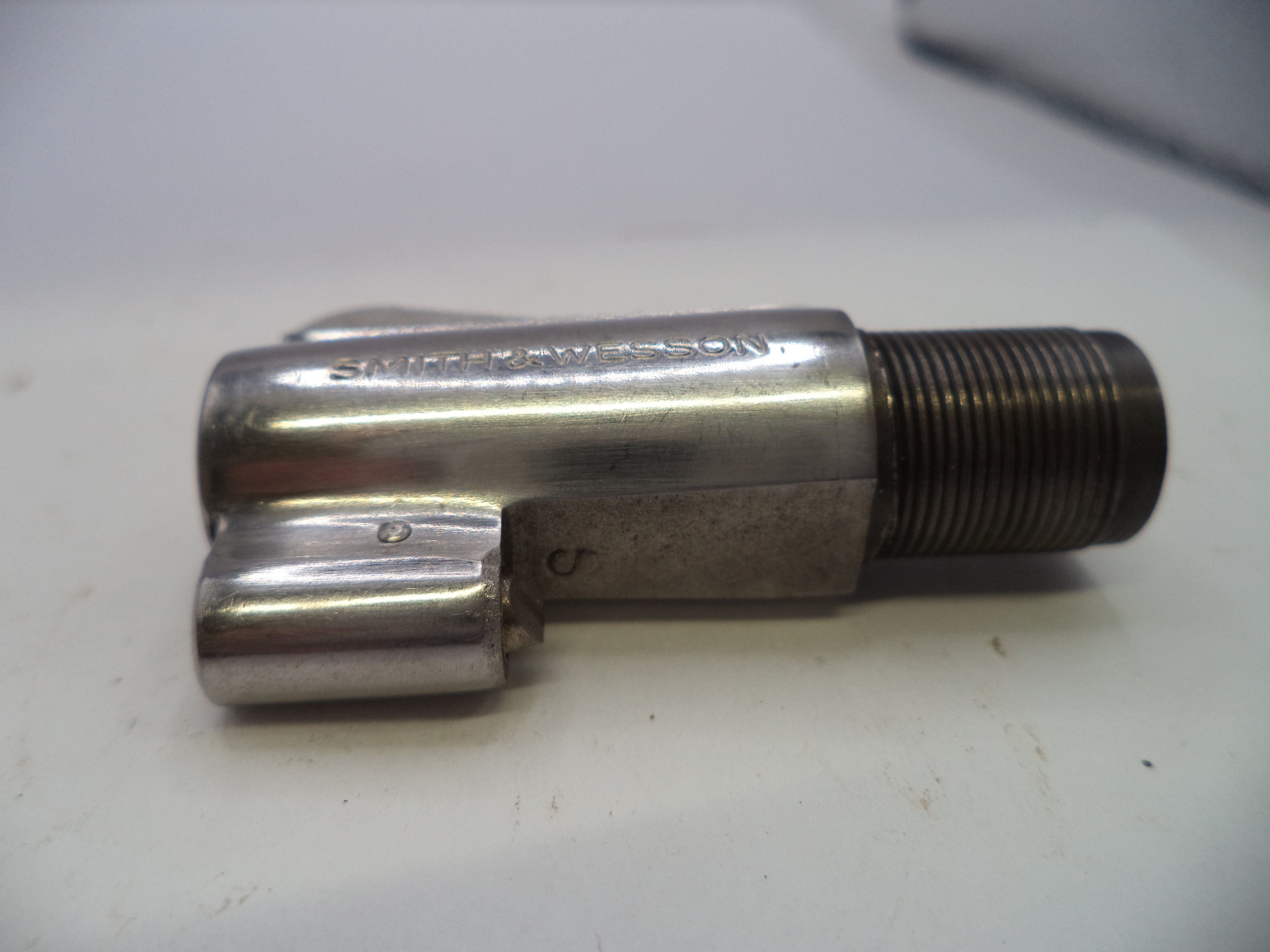 A used metallic bicycle headset component with a threaded bearing race, resting on a white surface.