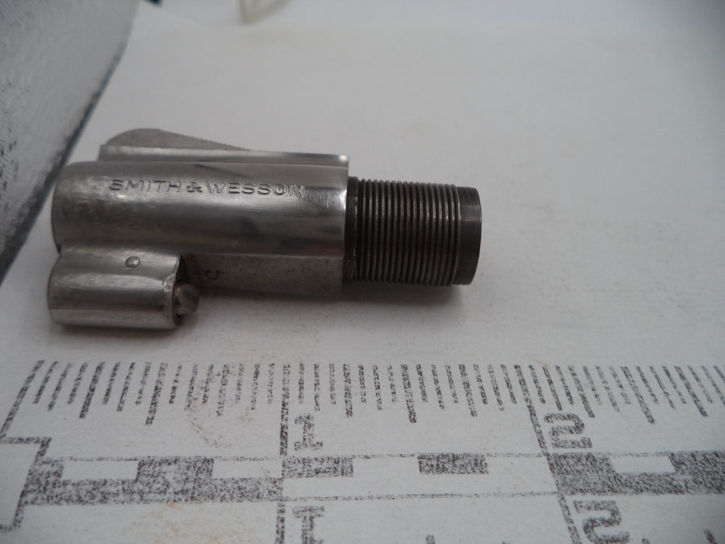 A vintage metal Smith & Wesson tool or hardware component with a threaded male end, resting on a printed paper background.