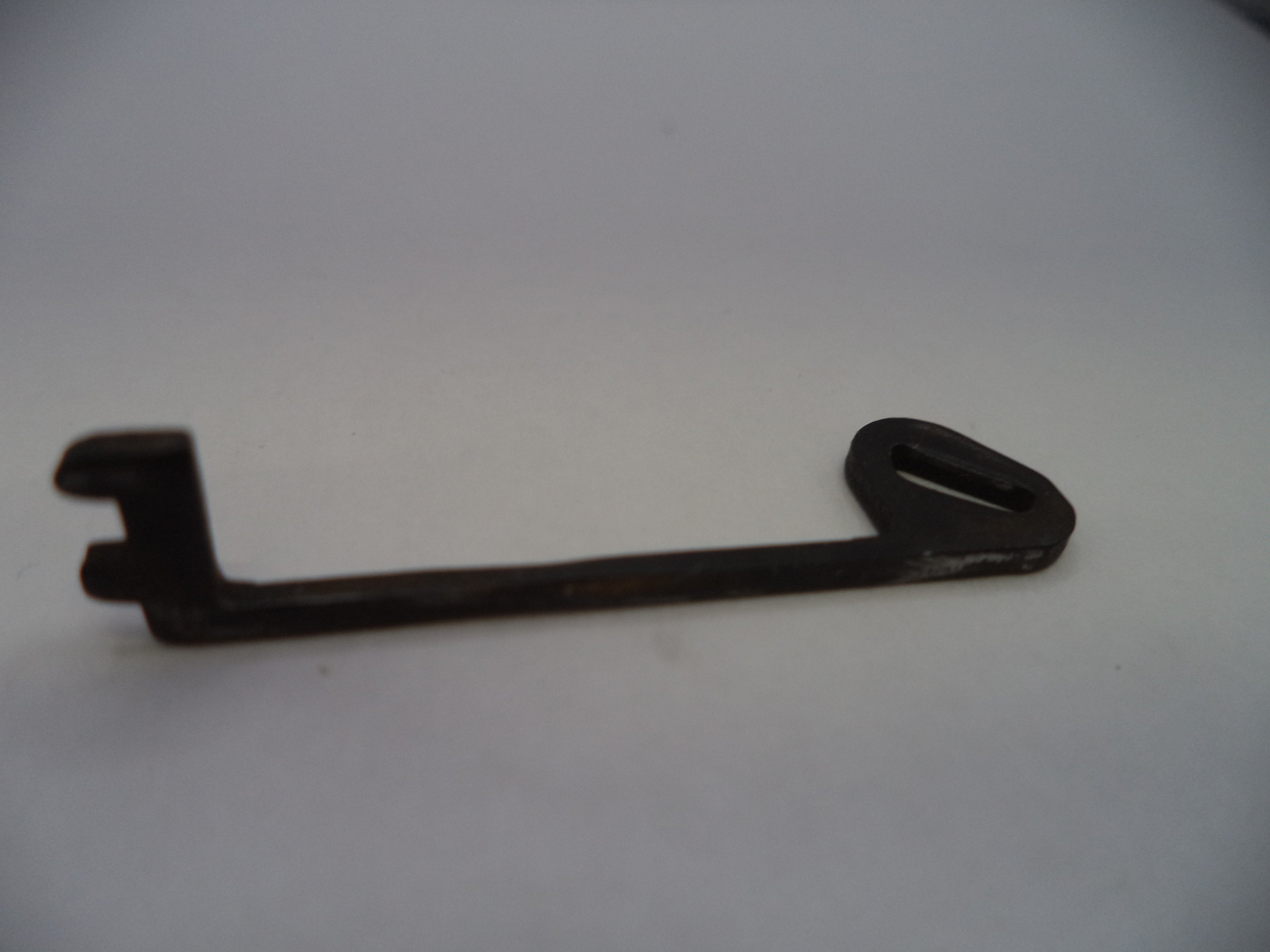 A small dark metal key-shaped tool or accessory with a looped end, photographed on a plain light background.