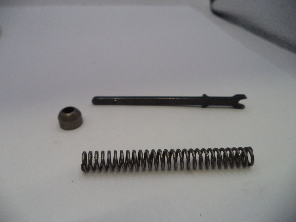 A small metal mechanical repair part set consisting of a long black metal pin with a bent tip, a small dark metal cap, and a coiled metal spring, arranged on a plain white surface.