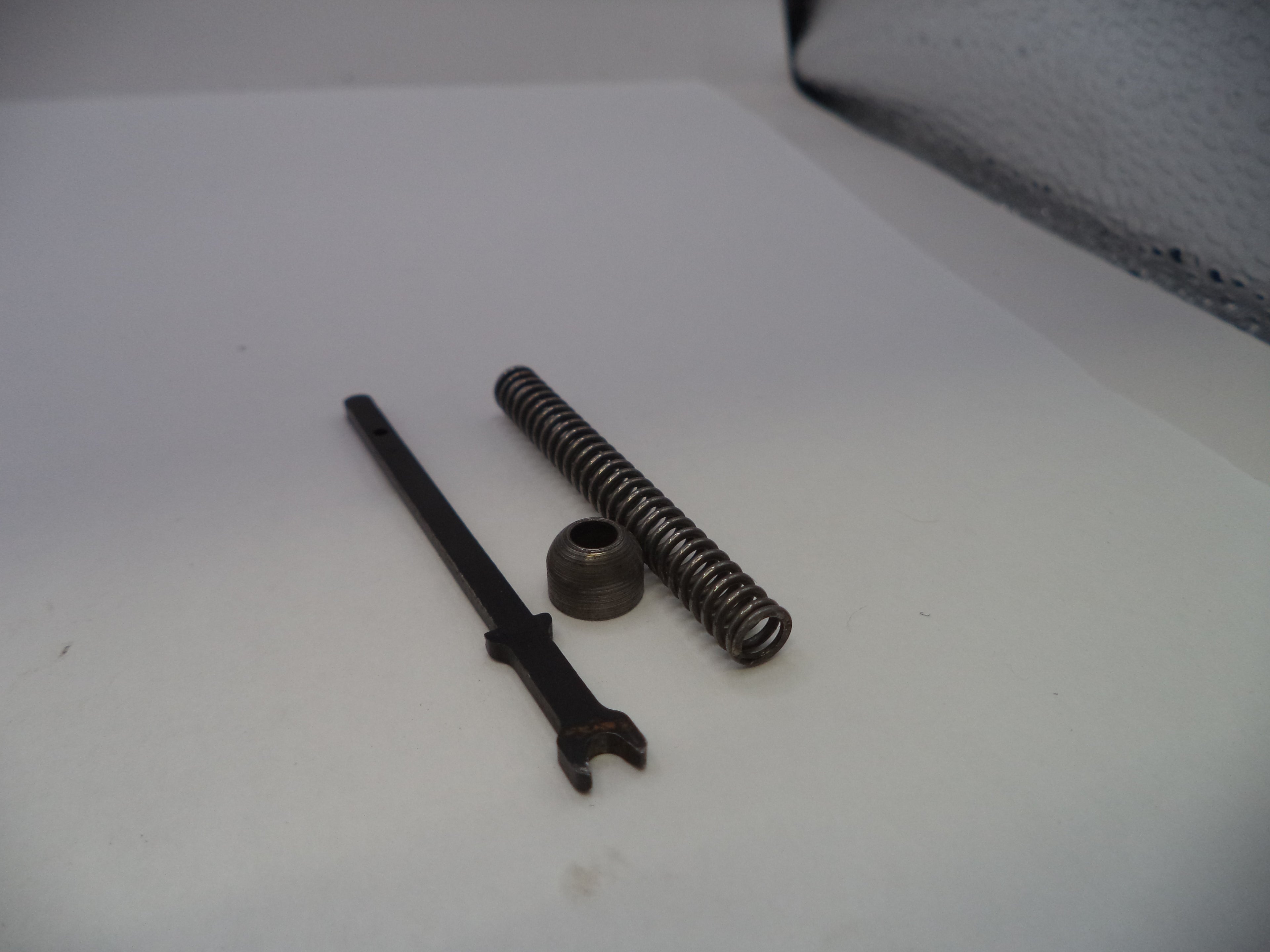 A small mechanical disassembly set containing a black metal pin, a coiled black spring, and a small black metal cap, displayed on a plain white surface.