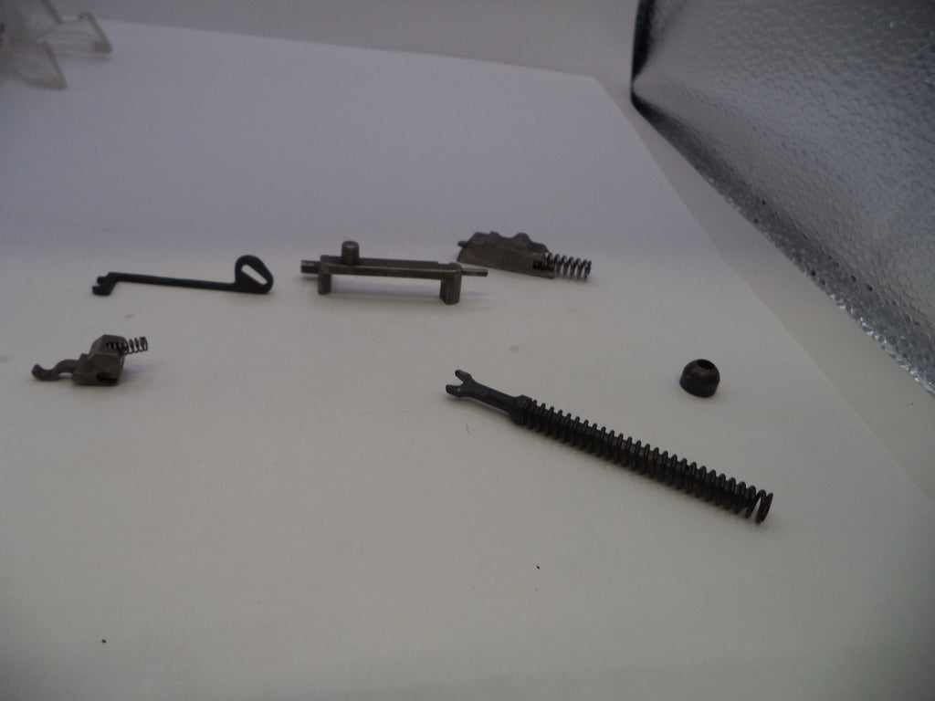 A set of small dark metal mechanical parts and springs arranged on a plain white surface.