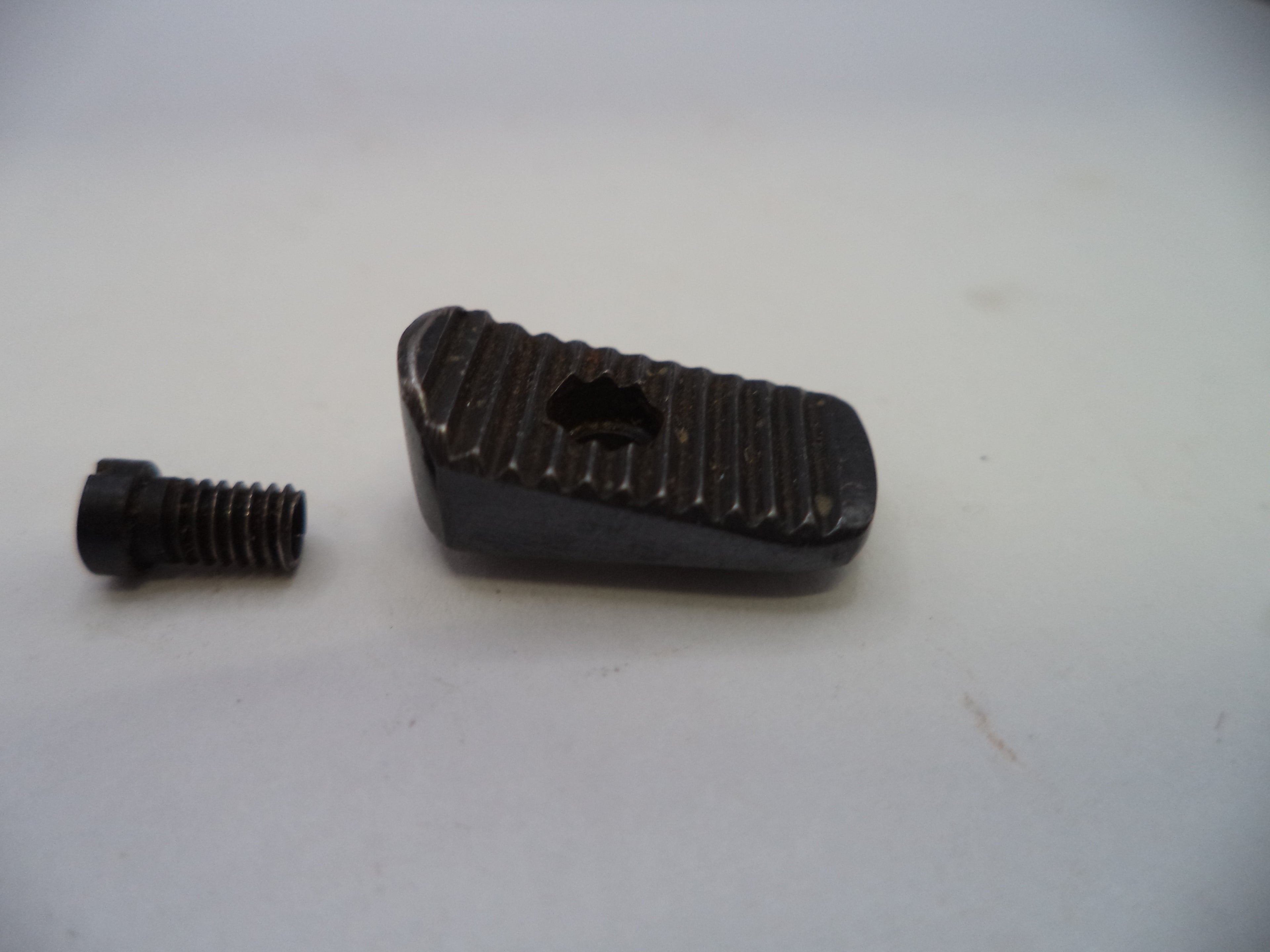 A small black metal hardware component, consisting of a textured rectangular piece with a central cutout and a separate matching threaded screw, shown on a plain light background.