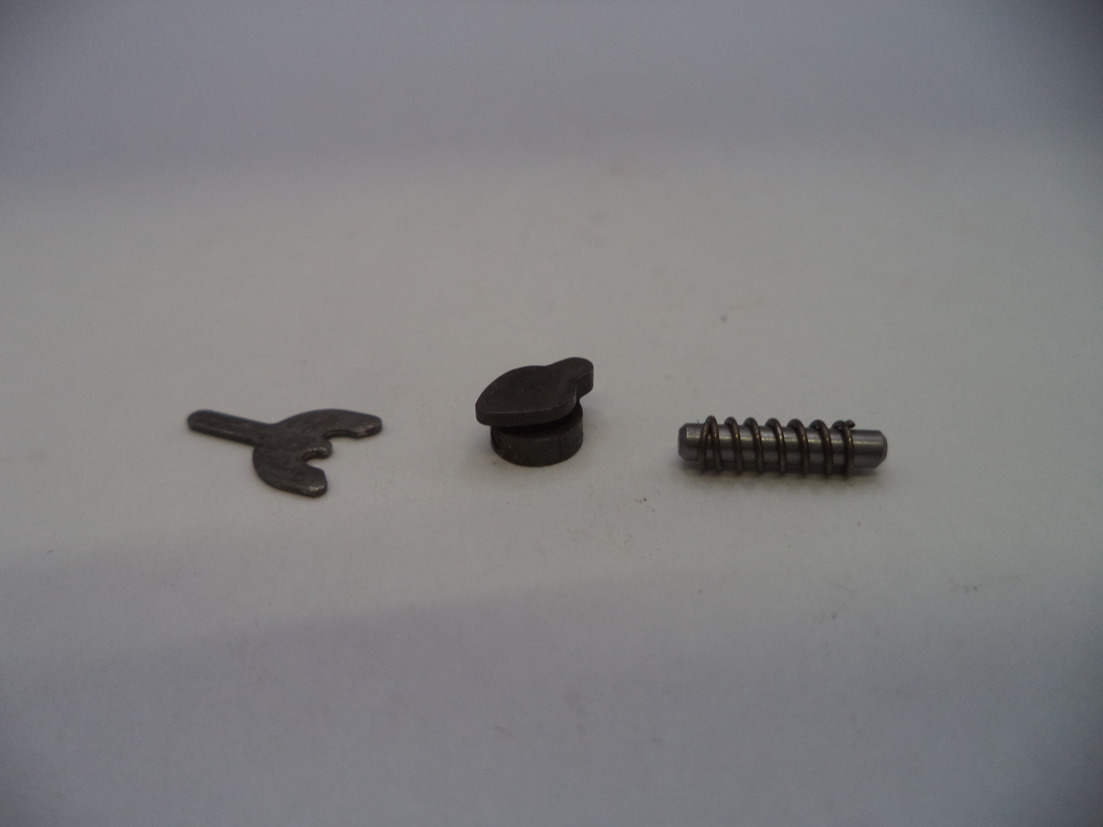 Three small metal hardware components, including a small flat piece, a round black cap, and a threaded screw, arranged on a plain light background.