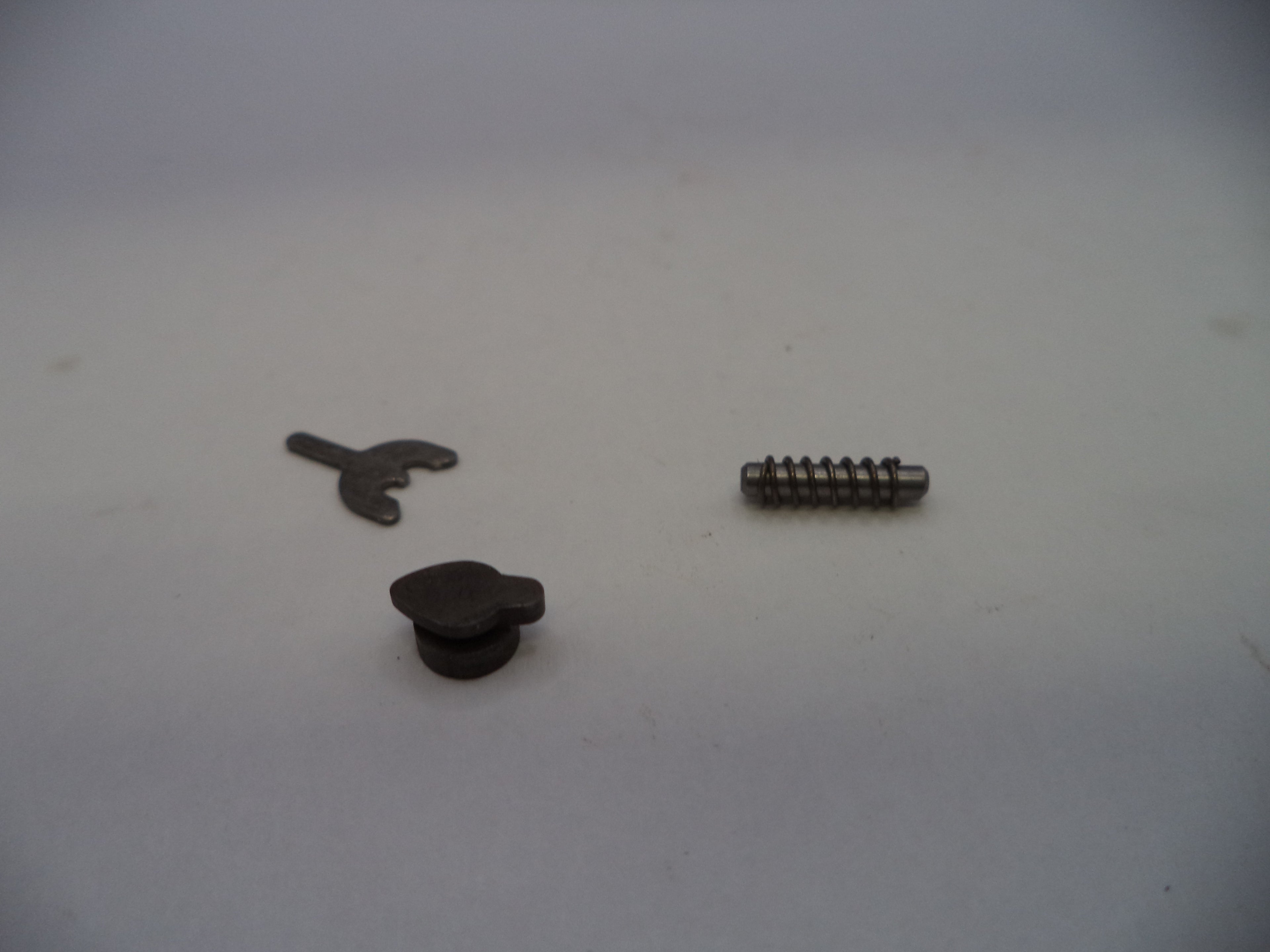 Three small dark metal hardware components, including a small screw, a small flat tab, and a small round knob, arranged on a plain light background.