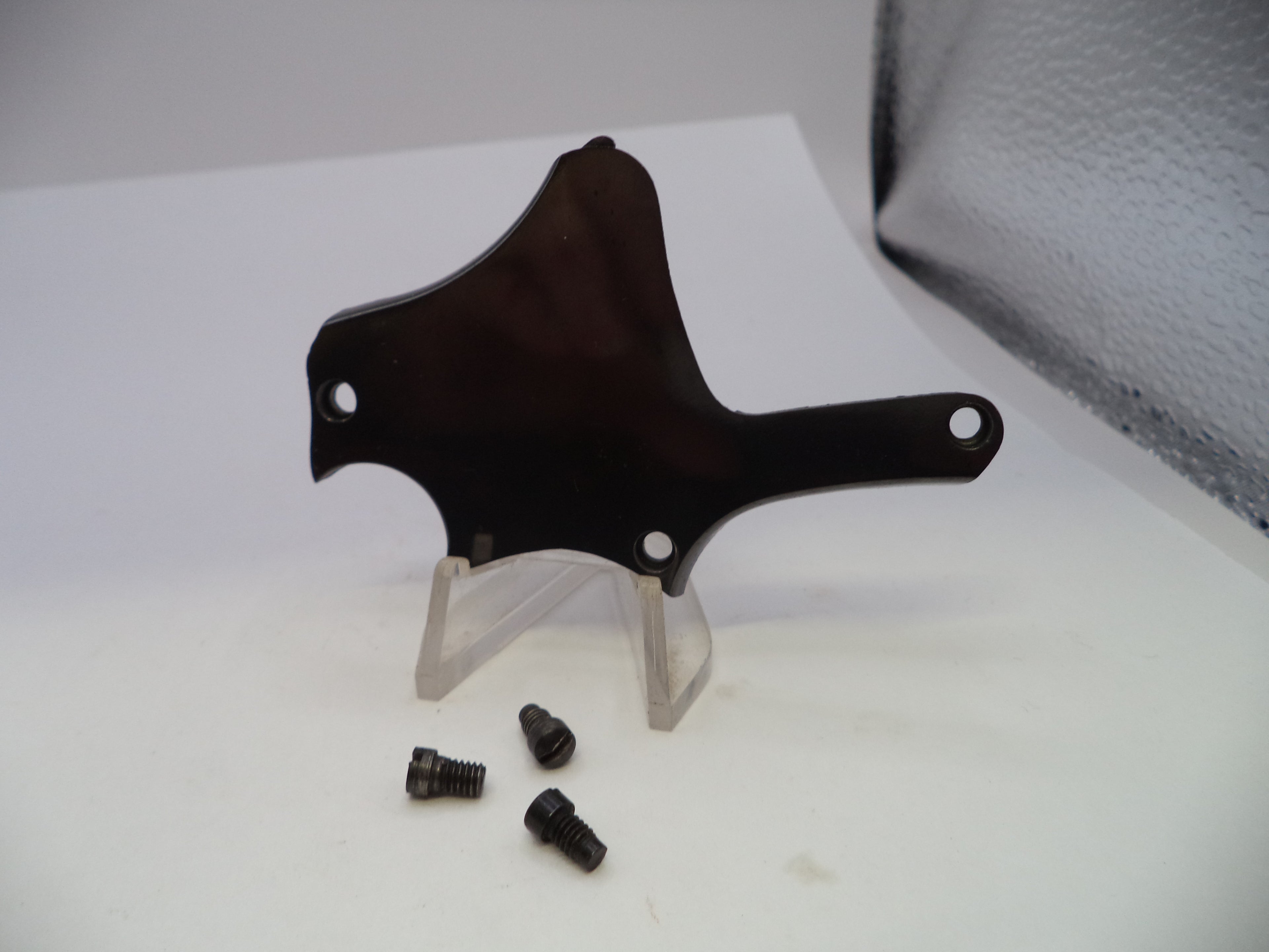 A dark brown wooden mounting bracket with pre-drilled screw holes, displayed on a clear acrylic stand with three small black screws below it, set against a white background.