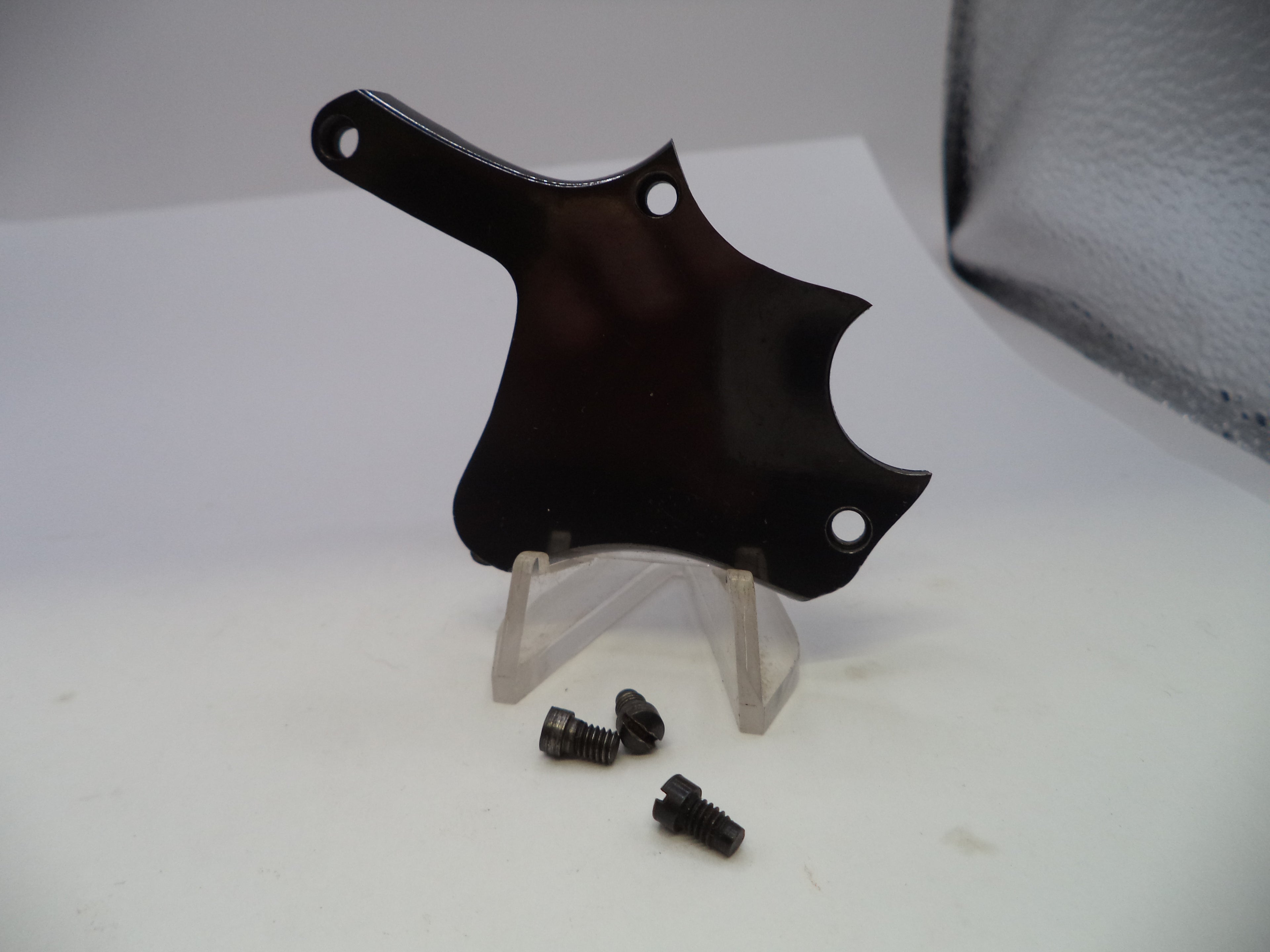 A glossy black plastic guitar pickguard with pre-drilled mounting holes, displayed on a clear acrylic stand with three small black screws below it, set against a plain white background.