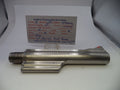 A metallic cylindrical gun part with a threaded end and a flat side, photographed on a white surface with a handwritten parts card behind it. The card reads Smith & Wesson Revolver Parts and includes caliber and part details.