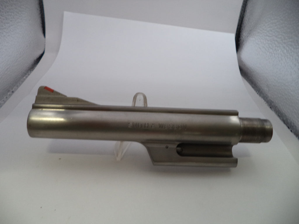A metallic gun barrel or receiver component displayed on a clear stand against a white background with gray textured side panels.