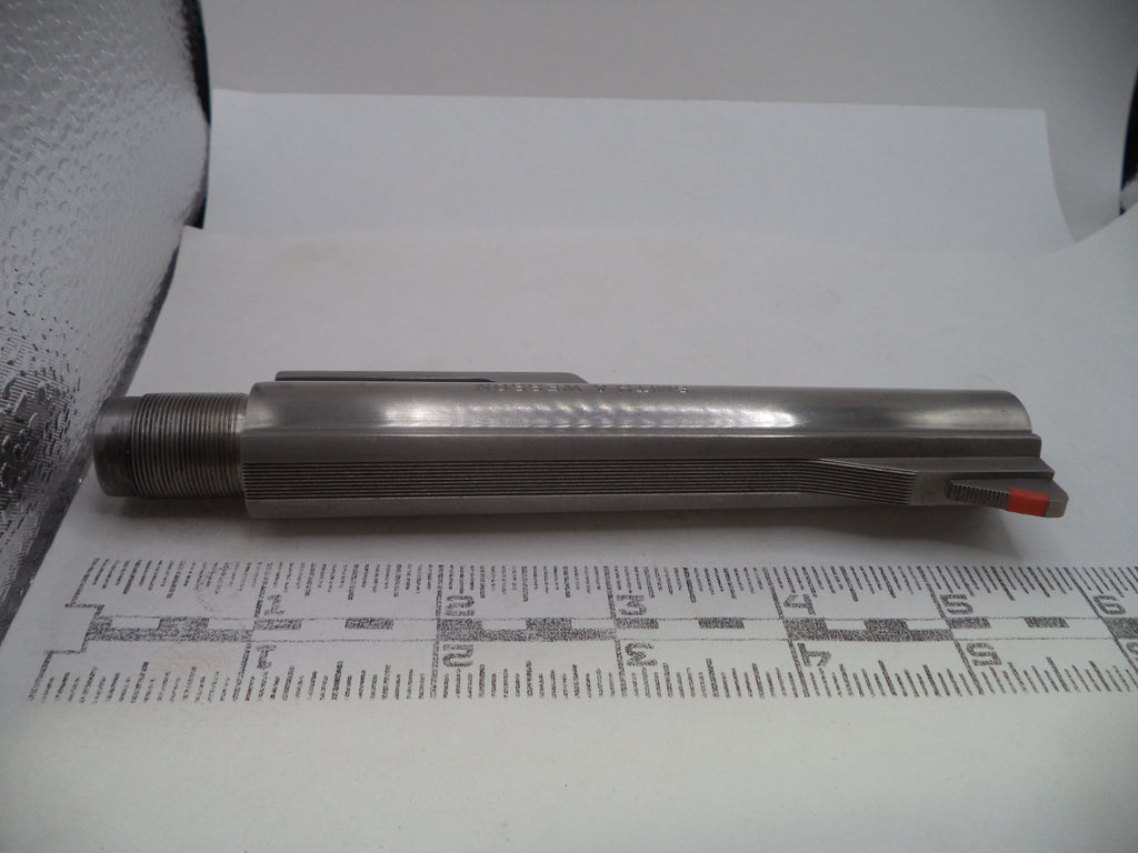 A metallic cylindrical tool or component with a threaded end and a small red accent, photographed on white paper above a measuring ruler.