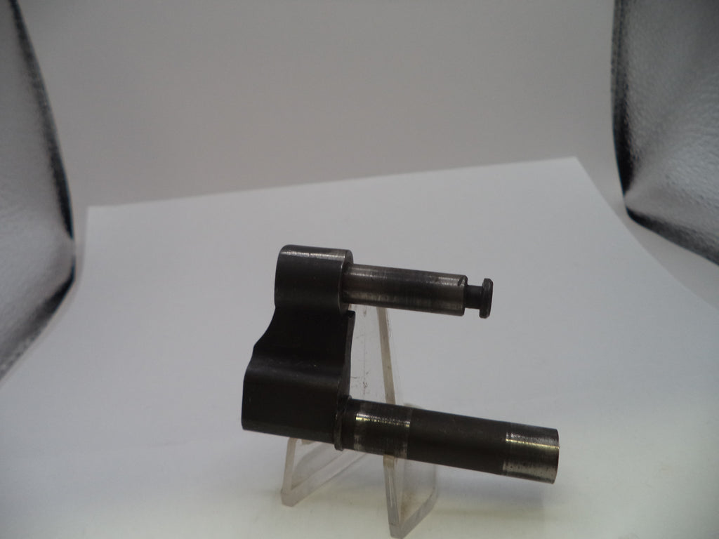 A dark metallic mechanical part, possibly a valve stem or throttle body component, displayed on a clear plastic stand against a white background with studio lights visible in the corners.