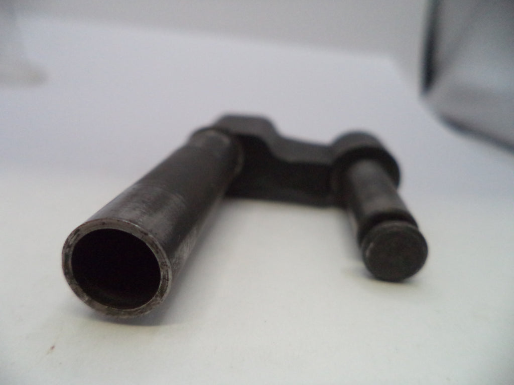 A dark metal mechanical part, possibly a valve stem or guide rod, resting on a white surface.