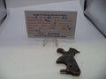 A dark metal revolver replacement part displayed on a white surface next to a handwritten parts identification card for a Smith & Wesson revolver.