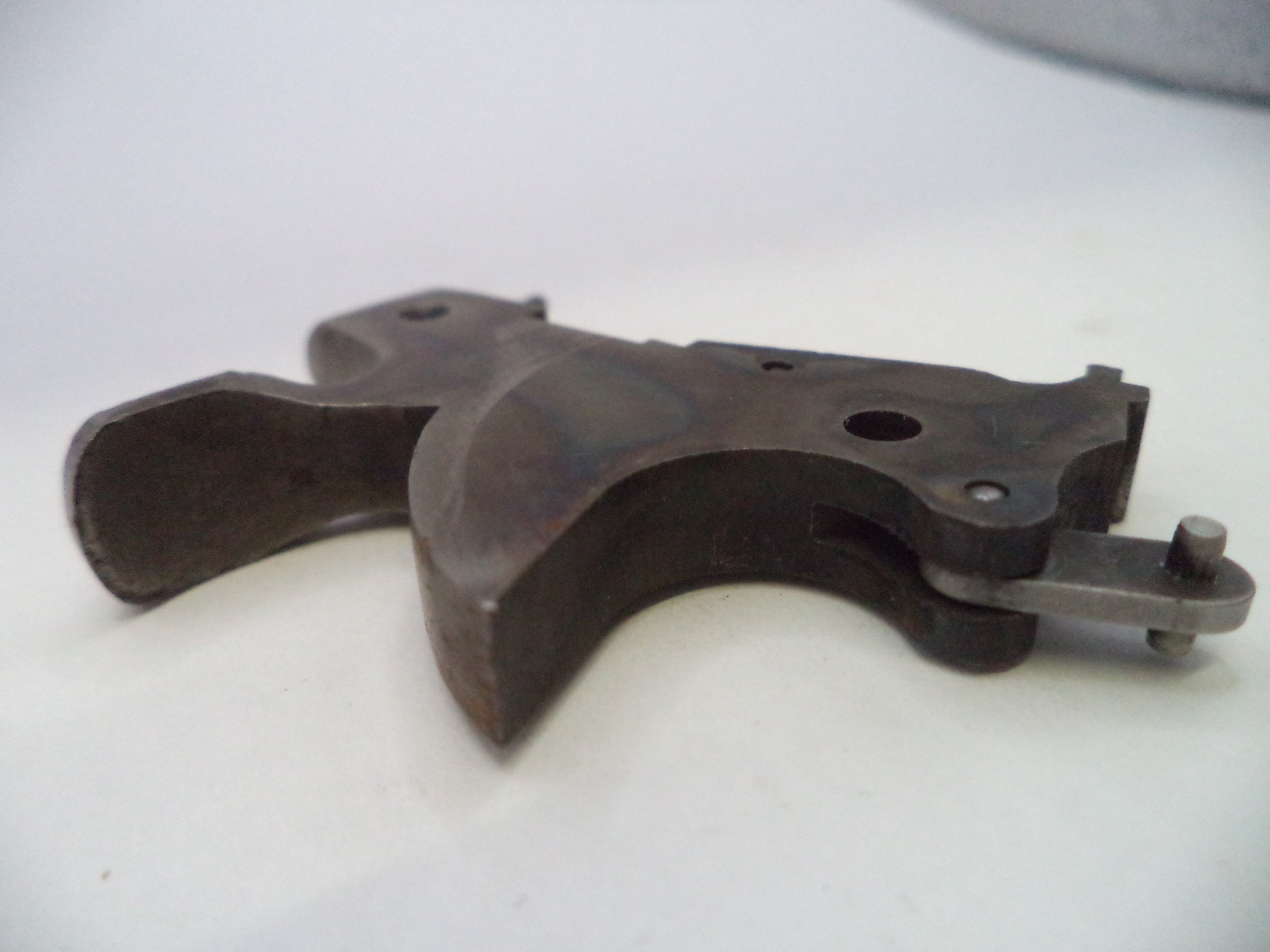 A dark metal firearm trigger assembly, likely a receiver or grip component, photographed on a plain light background.