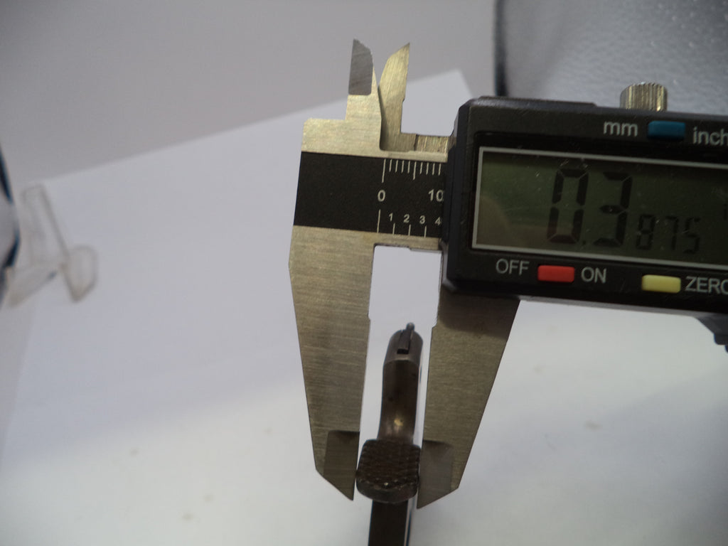 Digital calipers measuring a small metallic object on a white surface, with the display reading 0.3875 mm.