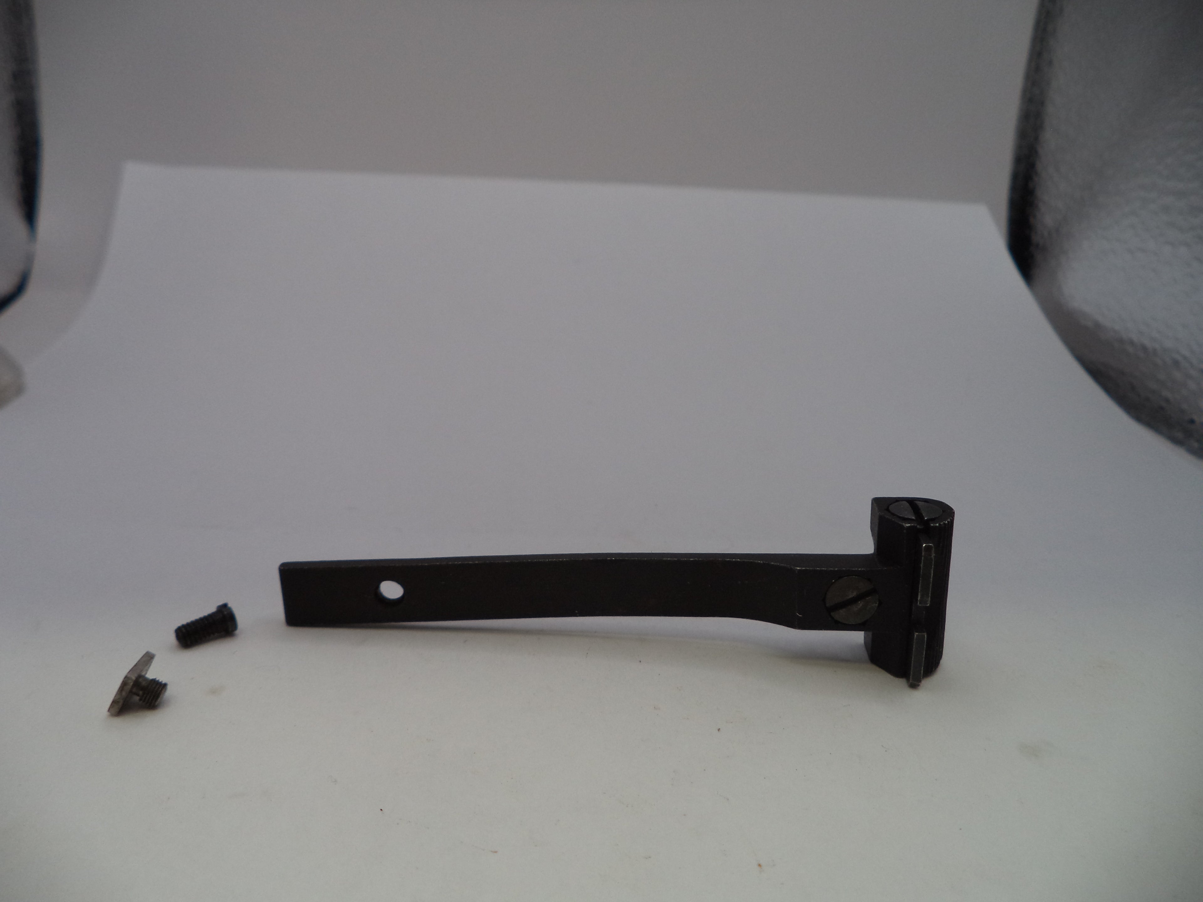 A black metal door lever or handle assembly with a small mounting hole, shown on a white surface with two small screws beside it.