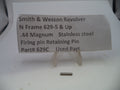 A small metallic retaining pin displayed on a clear plastic stand, with a paper label above reading 'Smith & Wesson Revolver N Frame 629-5 & Up .44 Magnum Stainless steel Firing pin Retaining Pin Part# 629C Used Part'.
