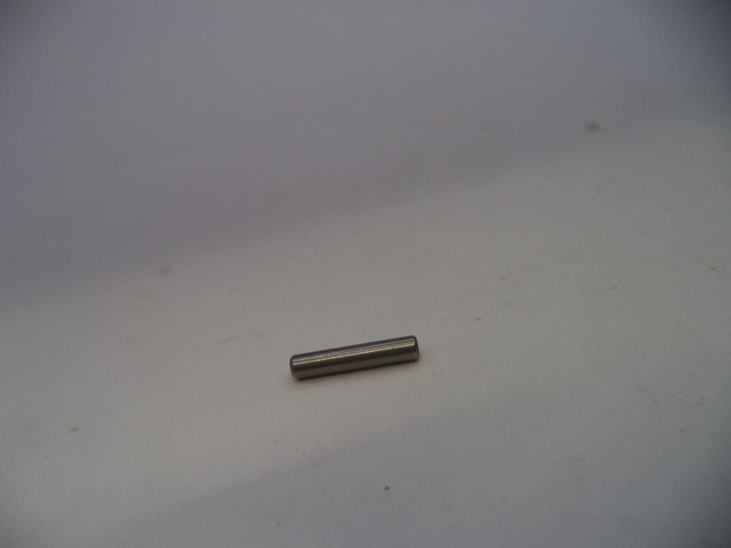 A small metallic cylindrical pin or rod lying horizontally on a plain light gray surface.