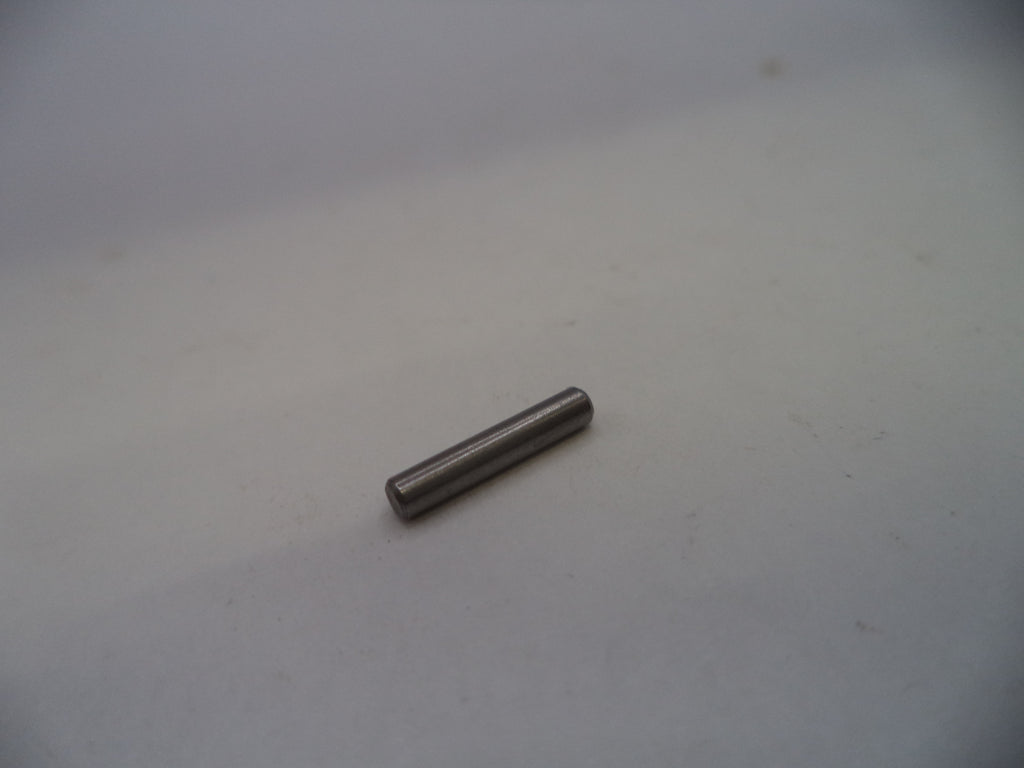A small metallic cylindrical pin or rod lying on a plain light gray surface.