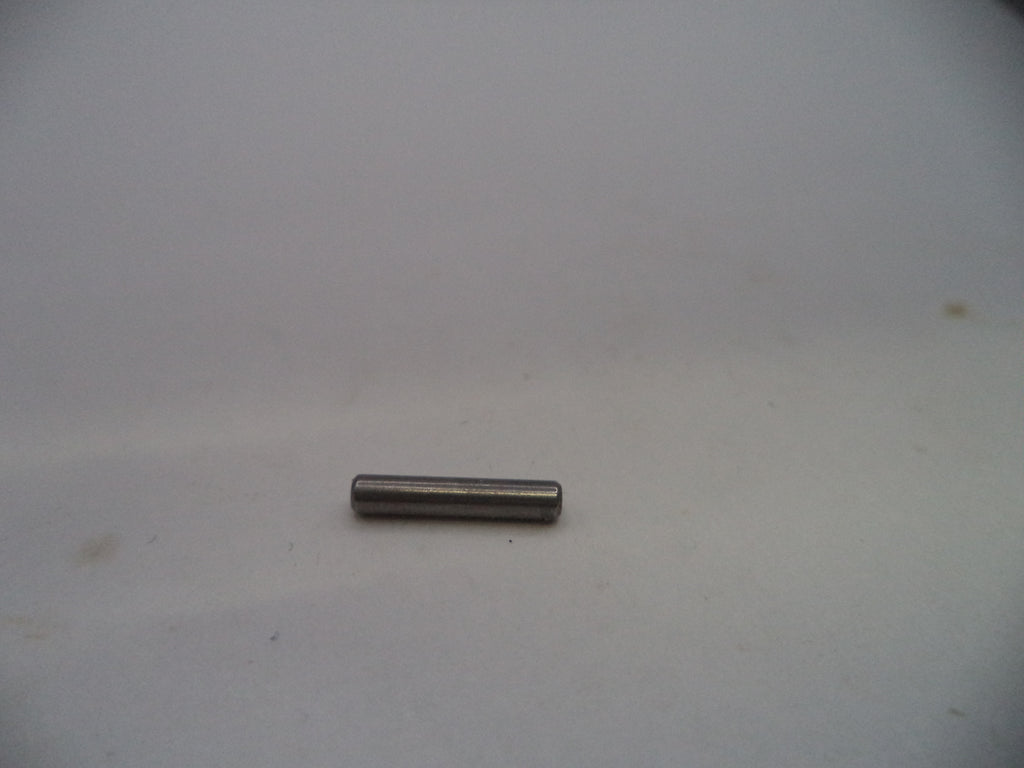 A small metallic cylindrical pin or rod lying horizontally on a plain light gray surface.
