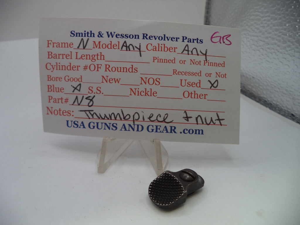 A small dark metal revolver part displayed in front of a handwritten parts list card on a clear stand. The card reads Smith & Wesson Revolver Parts and includes fields for caliber, barrel length, and part details, with USA GUNS AND GEAR .