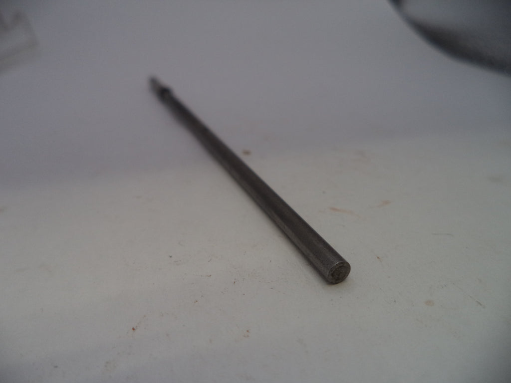 A single dark metallic screwdriver bit or small tool bit placed diagonally on a plain off-white surface.