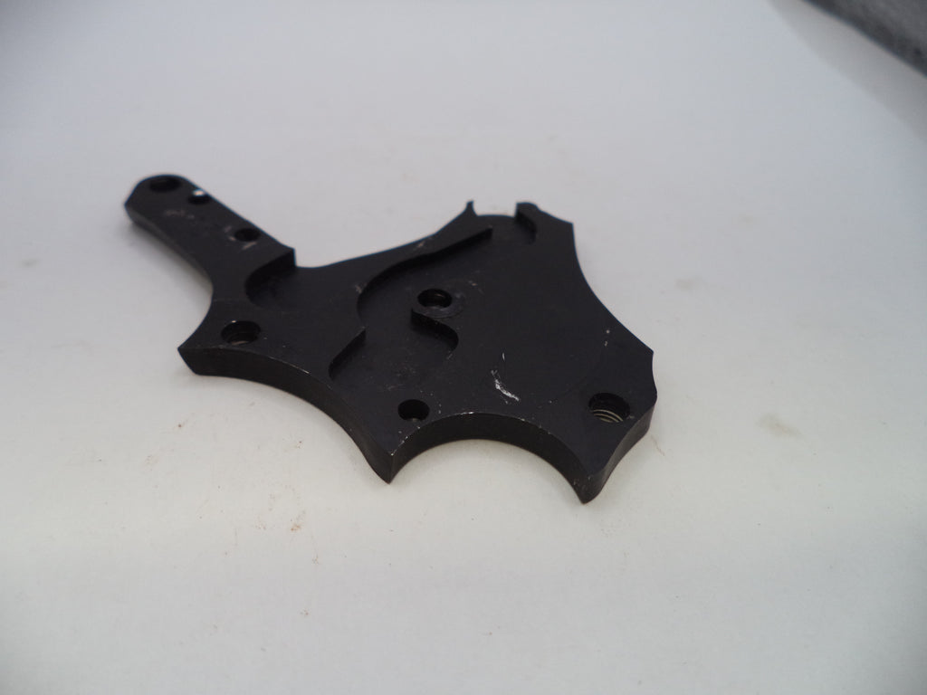 A black metal mechanical bracket or hardware piece with pre-drilled holes, photographed on a plain off-white surface.
