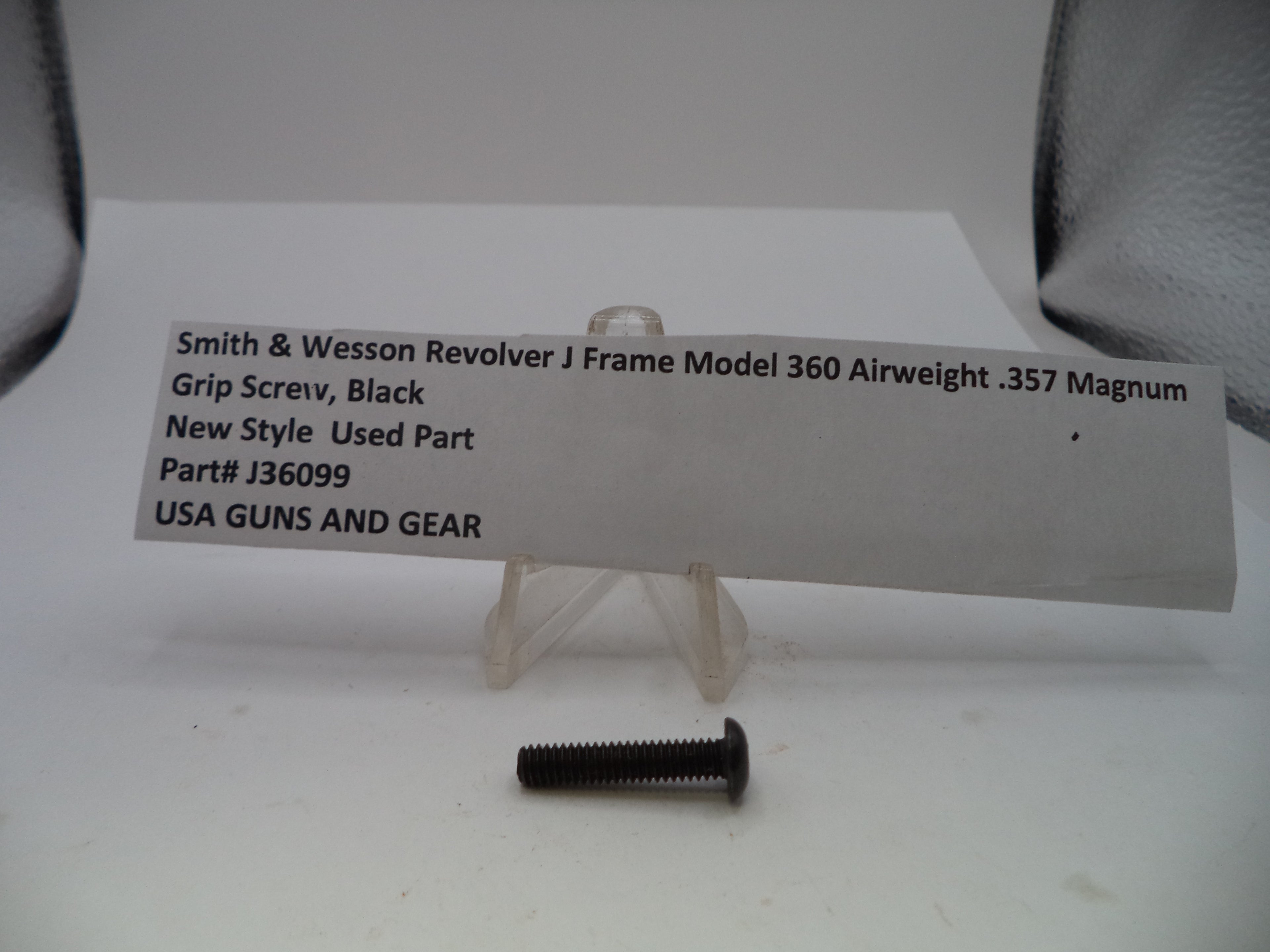 A single black metal grip screw for a Smith & Wesson Revolver J Frame Model 360 Airweight .357 Magnum, shown on a white surface with a paper label card in the background.