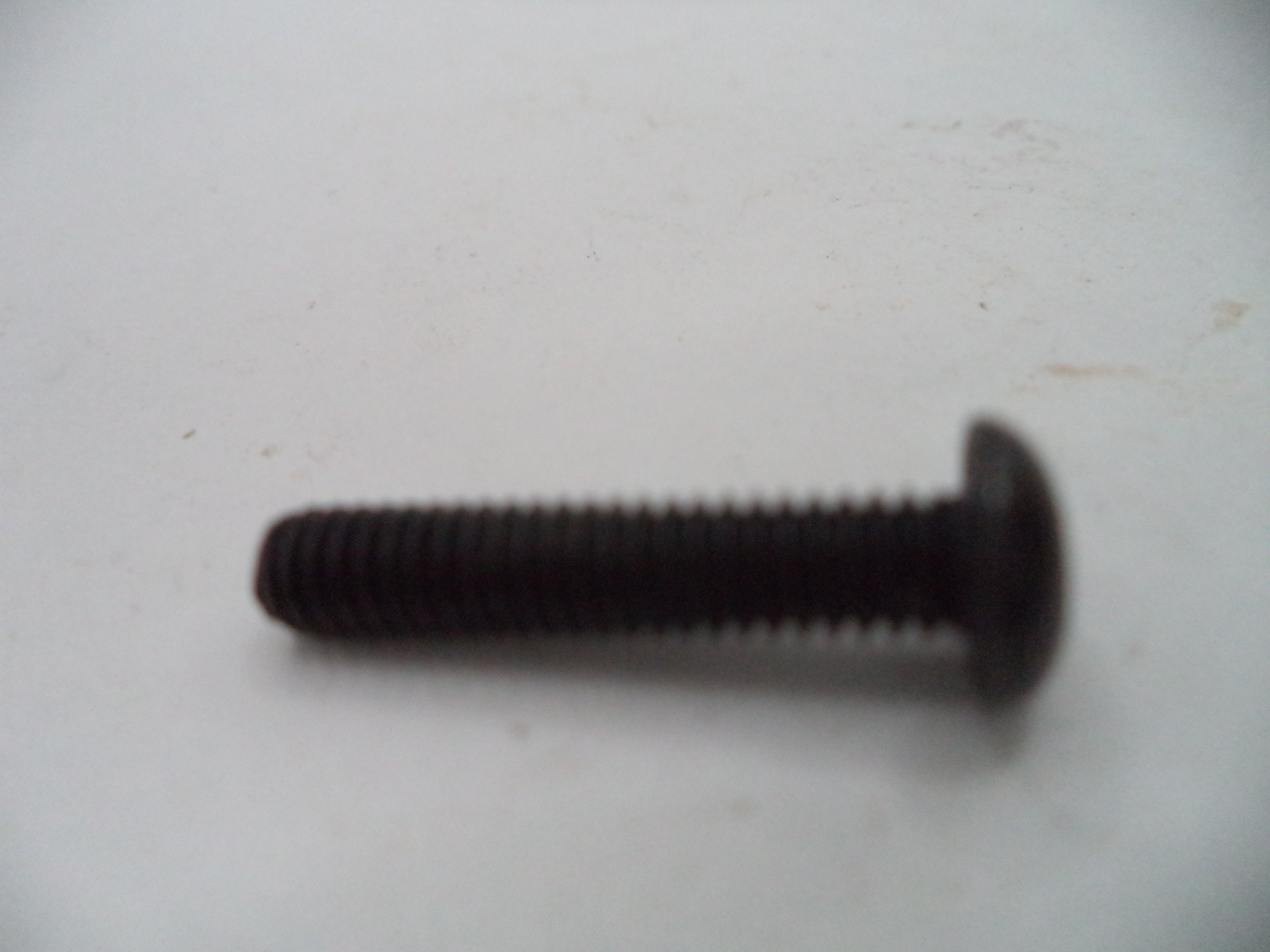 A single black metal flat-head screw with a threaded shank, shown on a plain off-white background.