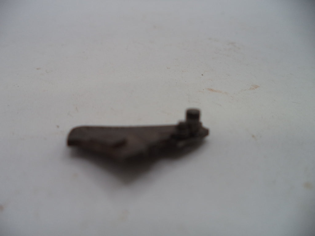 A small, dark, rusted metal mechanical part with a bolt, photographed on a plain off-white surface.