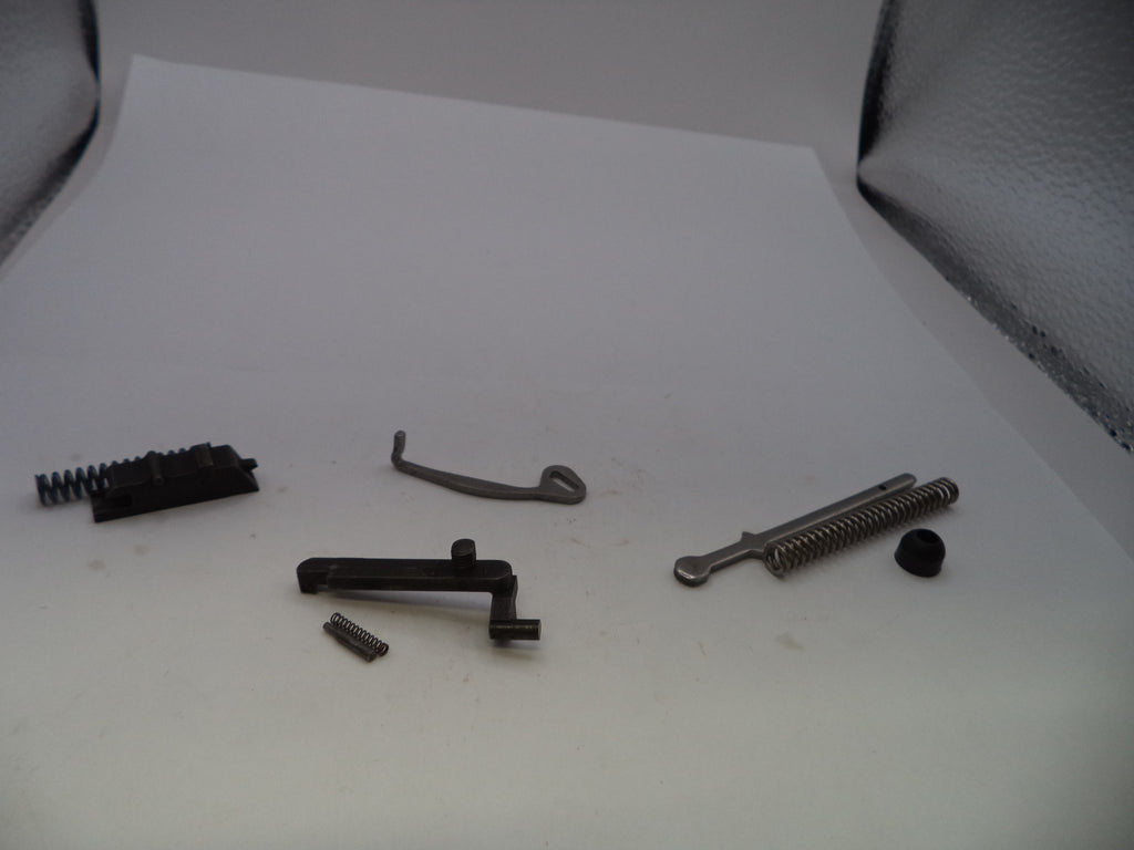 A set of small metal and black mechanical parts, including springs, a lever, and screws, arranged on a white surface.