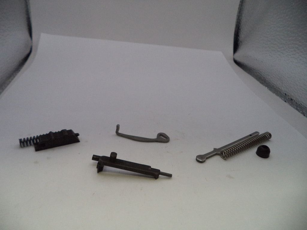 A set of small metal and black mechanical parts, including springs, rods, and a curved hook, arranged on a white surface.