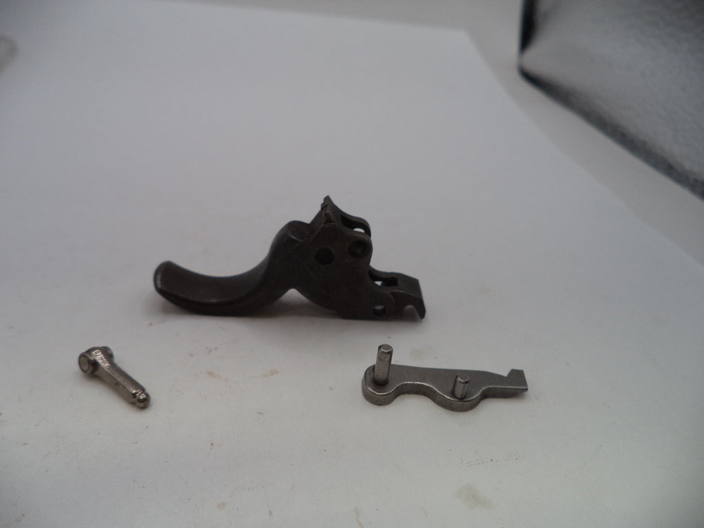 A black metal trigger assembly component shown disassembled with two small silver screws on a white surface.