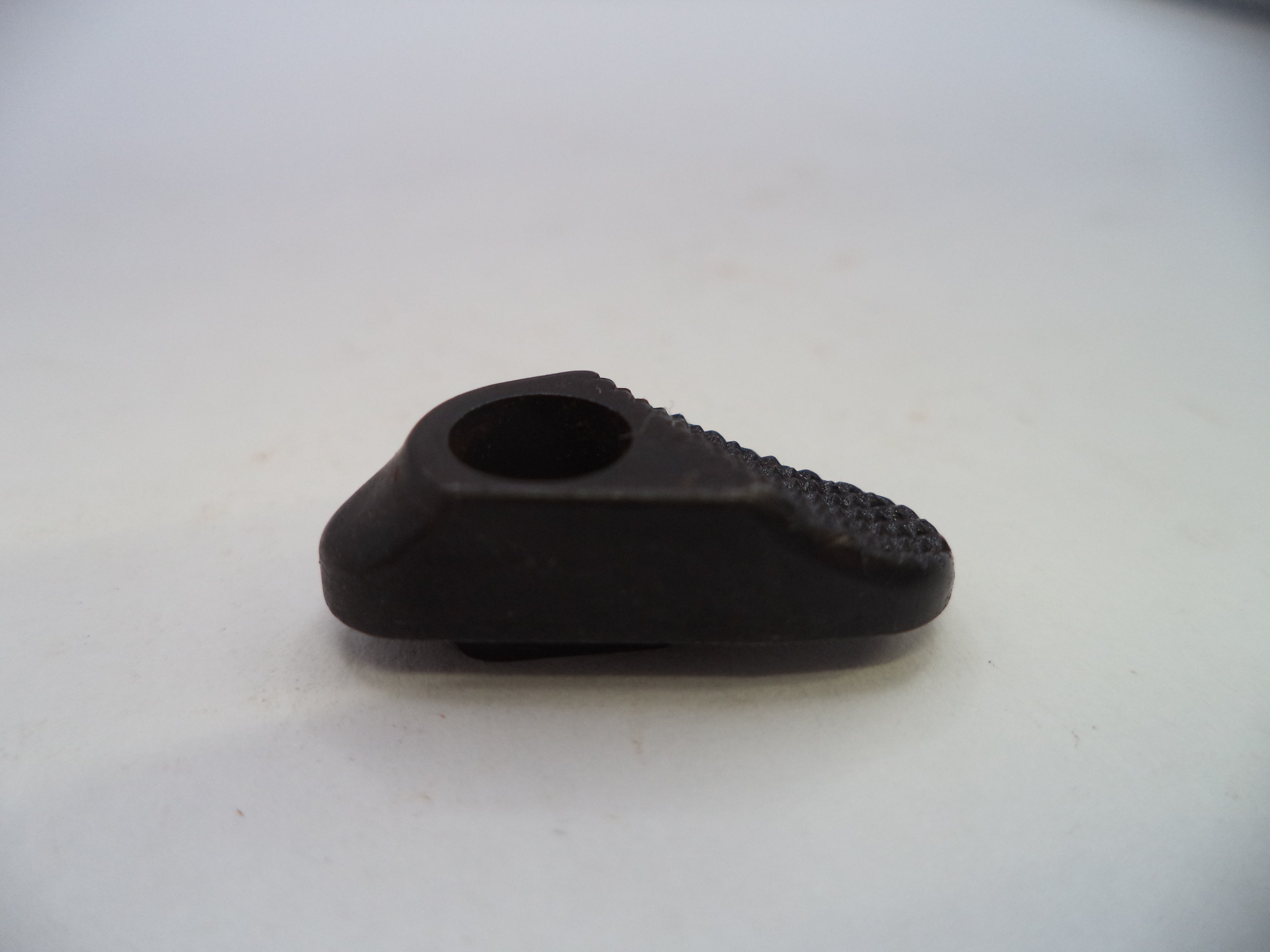 A small black plastic or rubber component with a circular opening and textured ridges on one side, photographed on a plain light background.