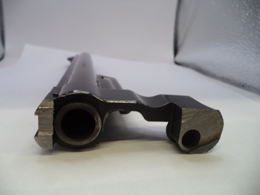 A close-up shot of a dark metal firearm receiver and barrel section on a white surface with a gray backdrop.