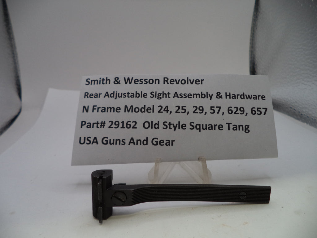 A black metal Smith & Wesson revolver rear adjustable sight assembly and hardware displayed on a small clear stand, with a white label card behind it showing product details.