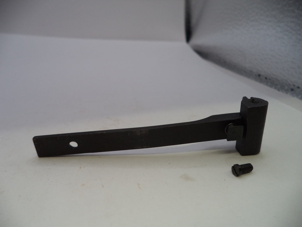 A black metal latch or bracket with a small mounting screw placed beside it, photographed on a light gray surface.