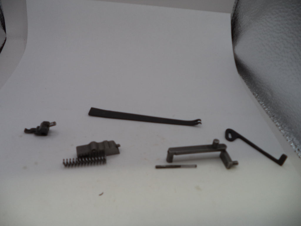A set of small dark metal mechanical parts and springs arranged on a plain white surface.
