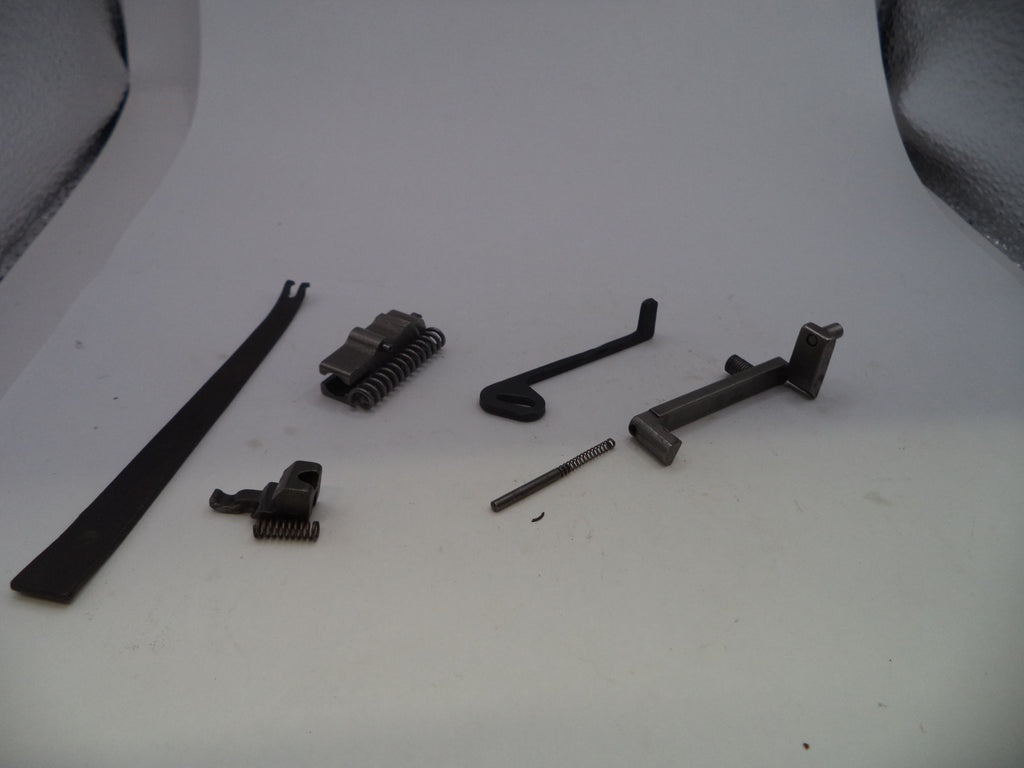 A set of small dark metal mechanical parts and springs arranged on a plain light background.