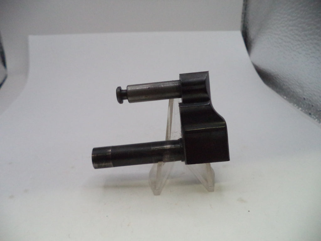 A small black metal mechanical component with two cylindrical shafts, displayed on a clear plastic stand against a white background.