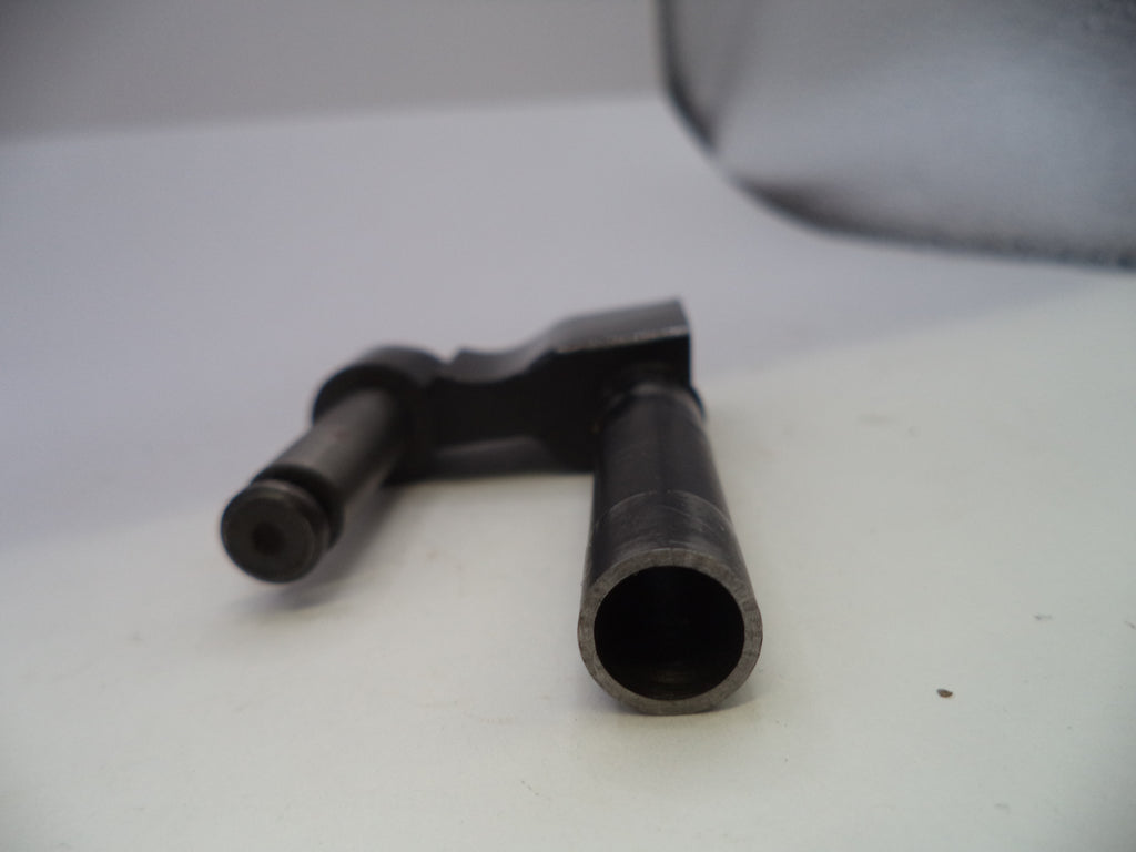 A close-up shot of a dark metal mechanical part, possibly a valve stem or throttle assembly, resting on a white surface.