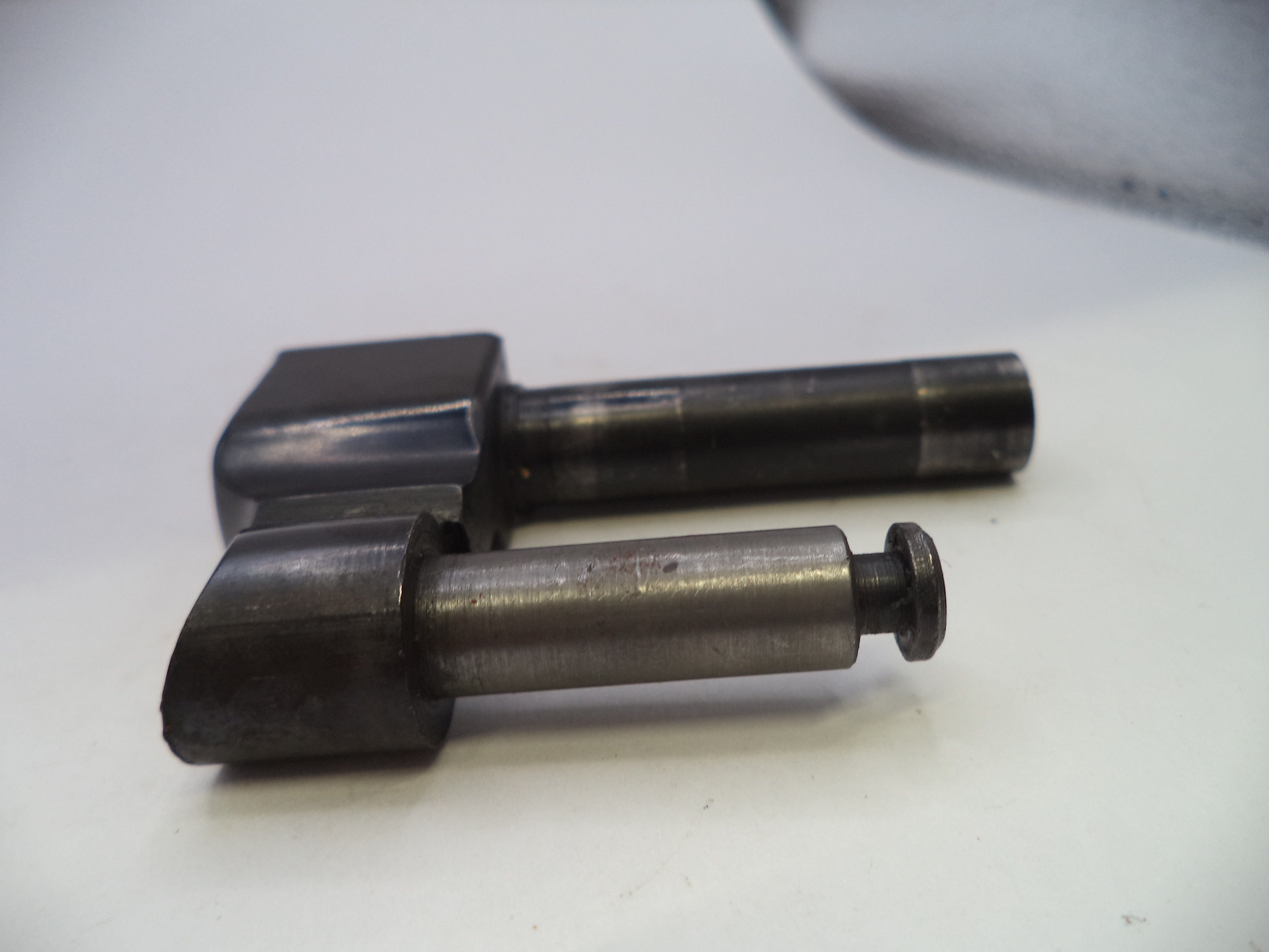 Two dark metal mechanical components with cylindrical shafts, photographed on a plain light background.