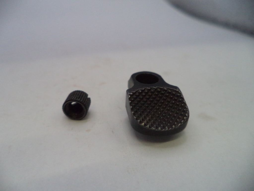 A close-up of a small black textured metal component and a separate matching cap on a light gray surface.